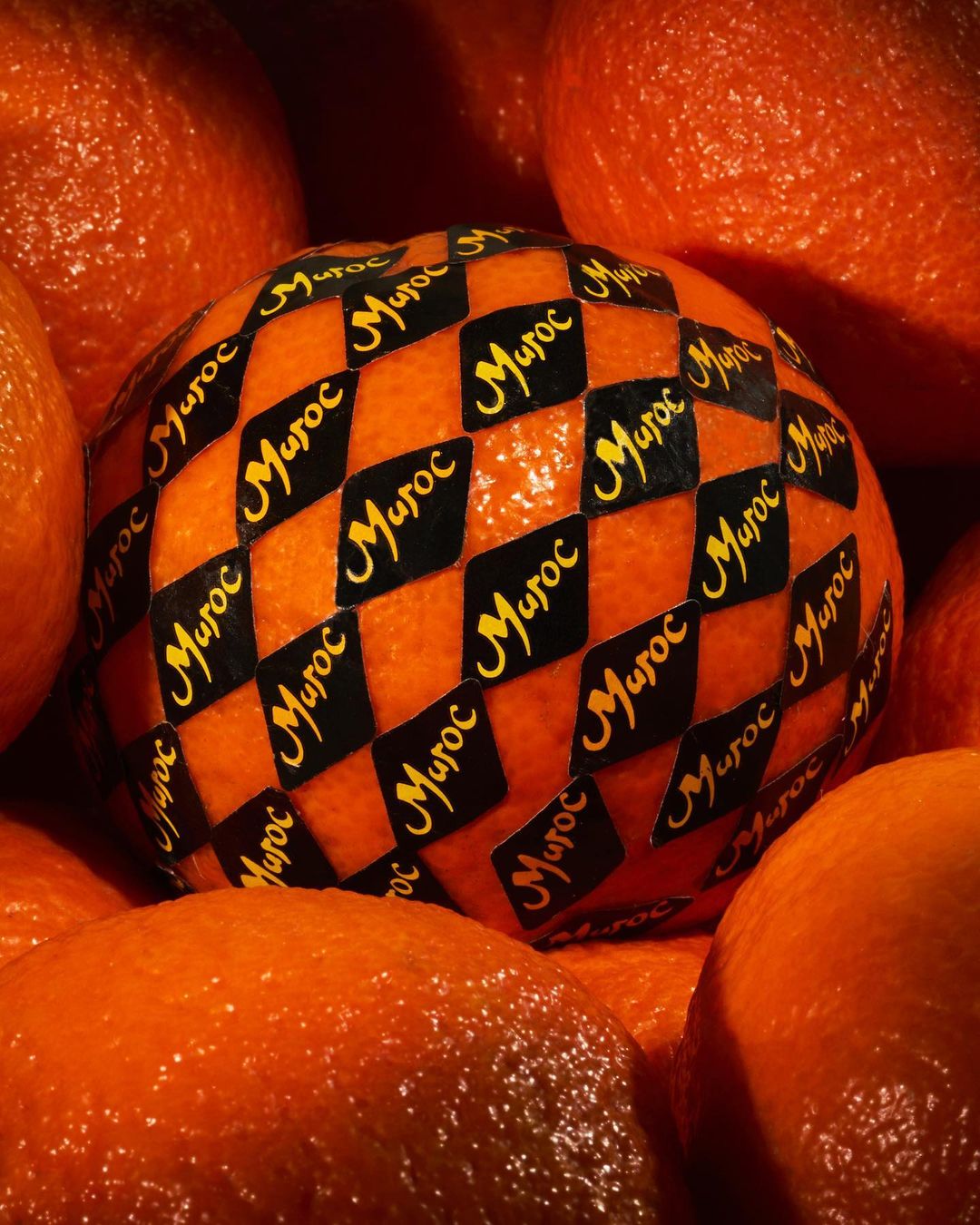 Close-up of tangerines, one labeled with 'Maroc', surrounded by others. The image highlights the texture and color of the citrus fruit.