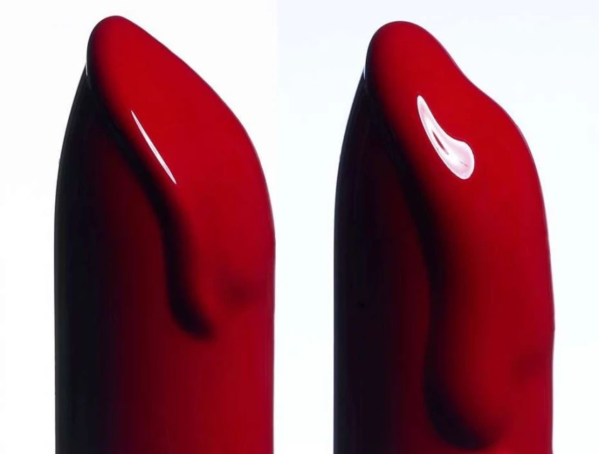 Close-up of two red lipstick bullets with a glossy, smooth texture against a bright white background, showcasing makeup details.