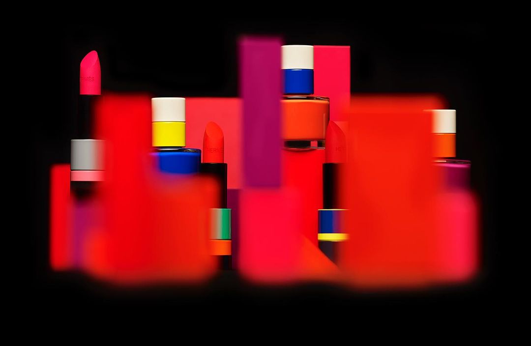 Eye-level studio shot of cosmetics on colorful geometric stands against a stark black background, showcasing beauty product photography.