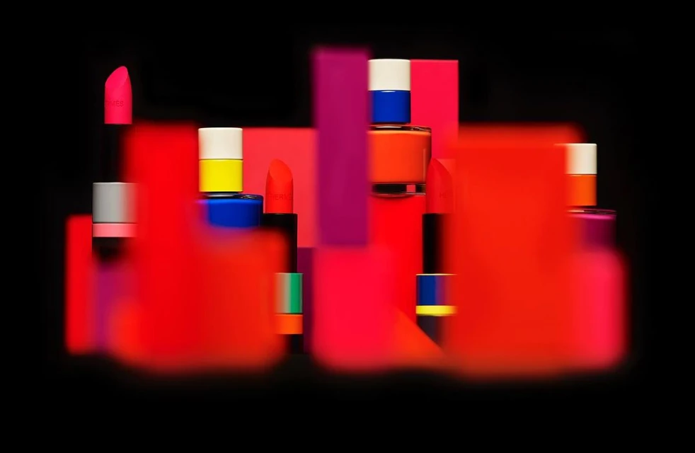 Eye-level studio shot of cosmetics on colorful geometric stands against a stark black background, showcasing beauty product photography.