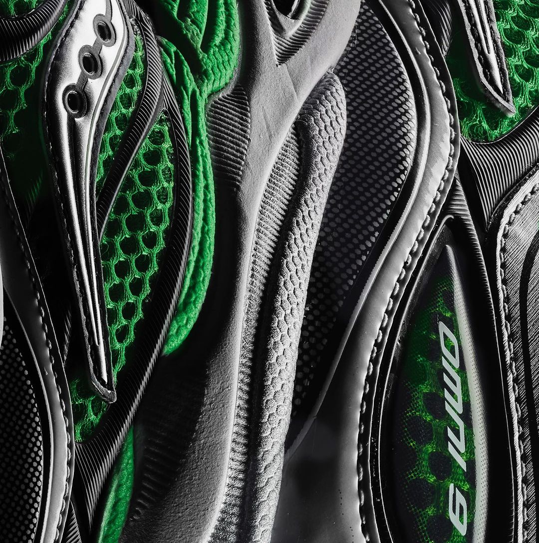 Close-up shot of a textured gray and black running shoe with green mesh, showcasing its design and material in detail.