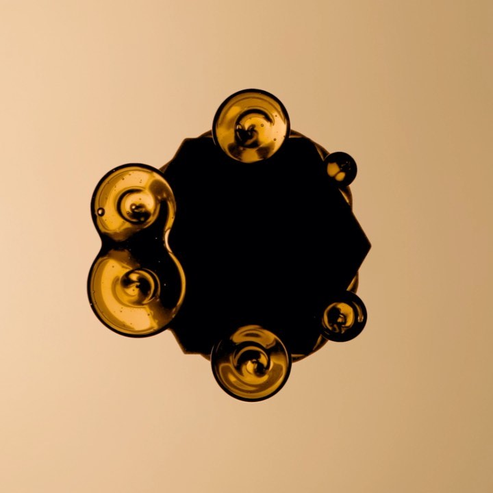 Abstract art featuring golden orbs surrounding a dark, geometric shape against a muted gold backdrop, creating a captivating visual composition.