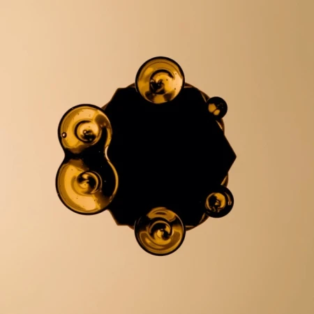 Abstract art featuring golden orbs surrounding a dark, geometric shape against a muted gold backdrop, creating a captivating visual composition.