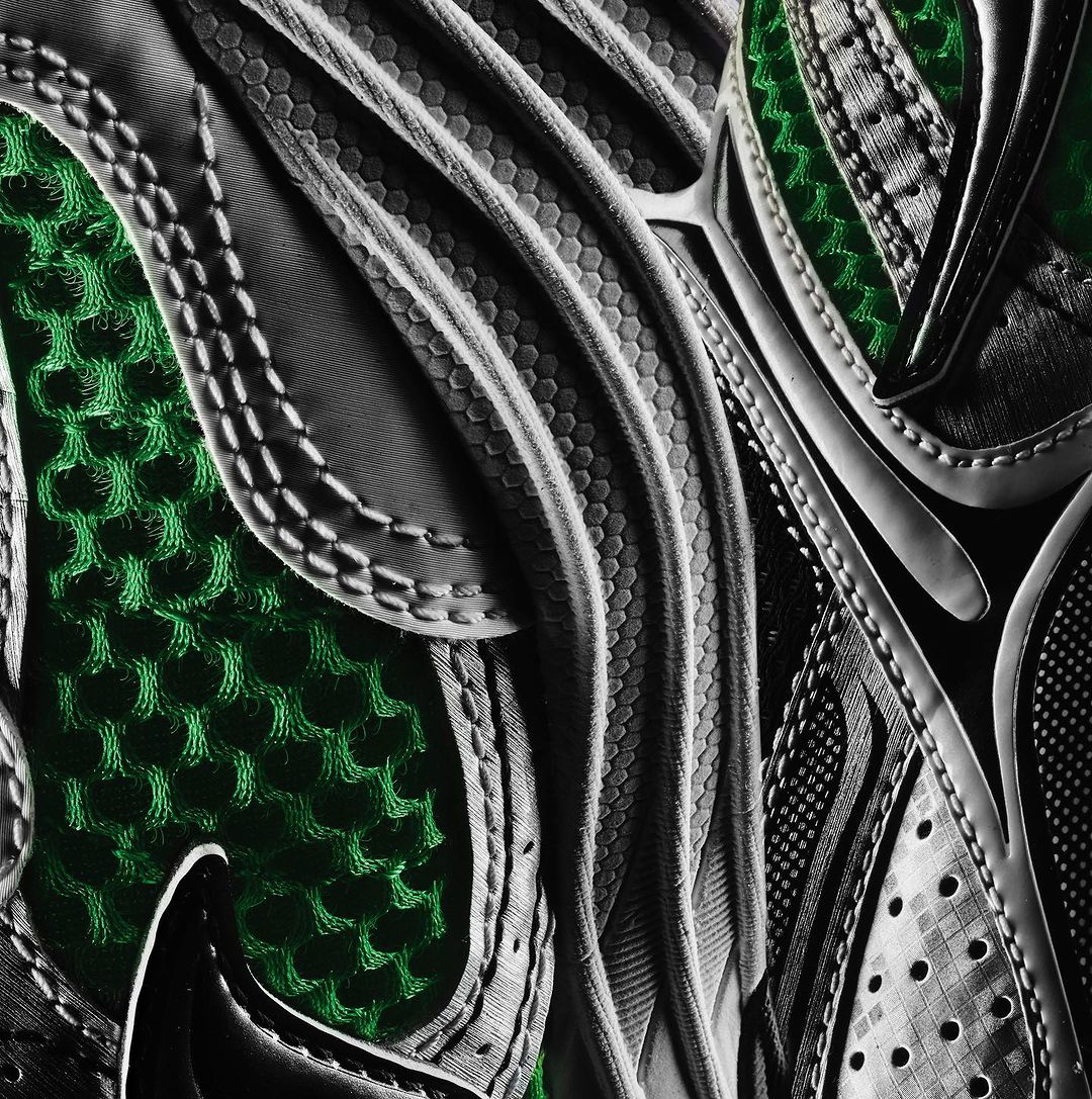 Close-up of a green and grey running shoe showcasing intricate patterns and textures, highlighting its sporty and modern design.