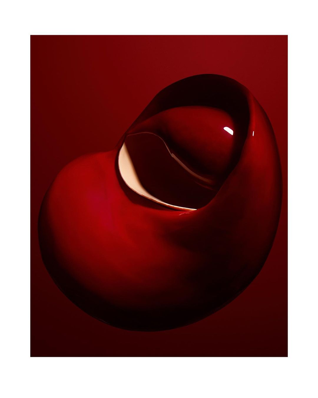 Abstract close-up of a fluid, sculptural form with a glossy texture in deep red tones, set against a matching monochromatic background.