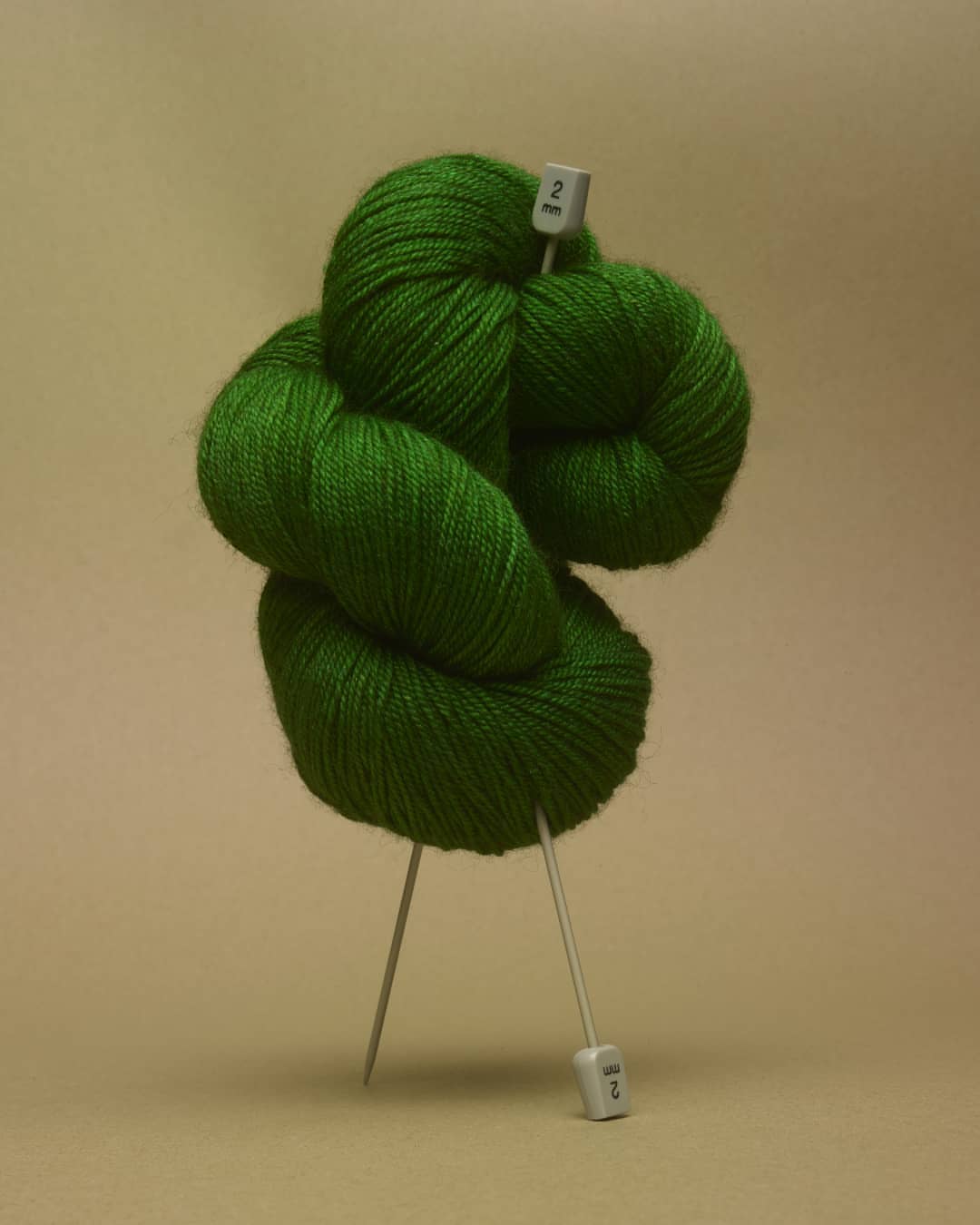 Still life shot of a bright green ball of yarn with knitting needles, creating a minimalist and colorful composition.