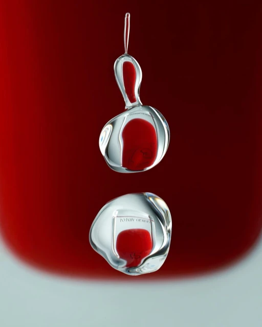 Two water droplets connected, one above the other, with a red background. The lower droplet has a reflection of text on it.