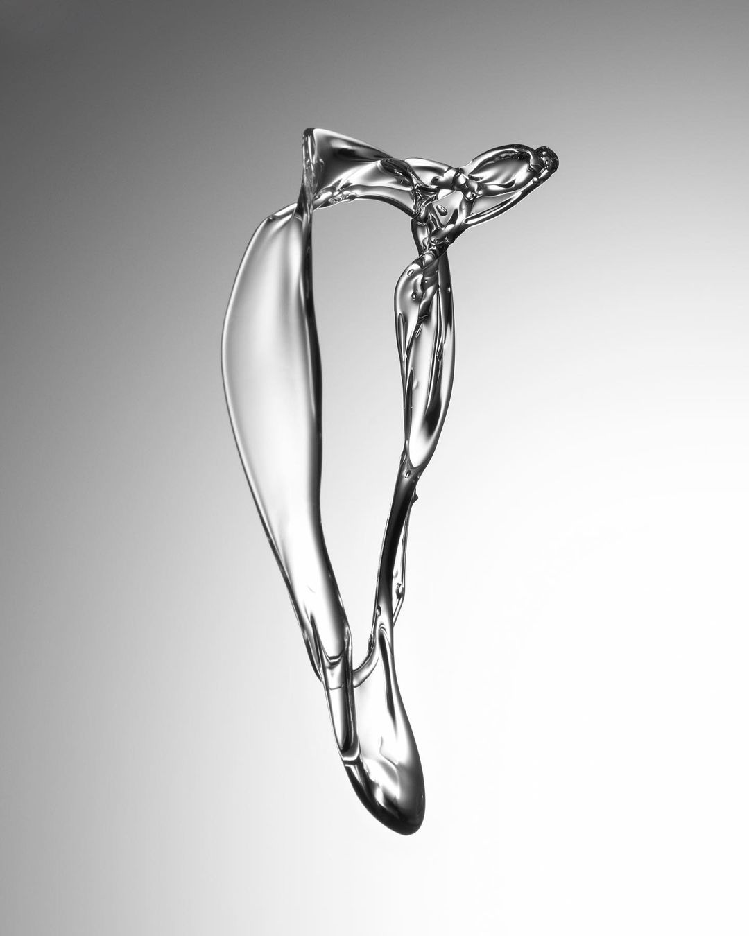 Abstract water splash shape against gray gradient background creating a sense of motion and fluidity in a studio setting.