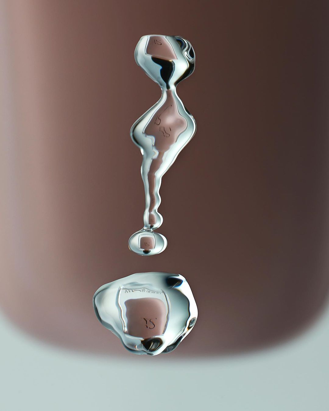 Abstract macro photograph of water droplets suspended in air against a blurred gradient background, with surface tension creating unique forms.