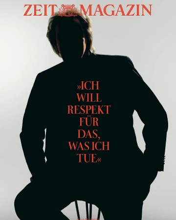 Silhouette of a man seated against a bright white background with large red magazine typography across his jacket.