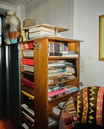Wooden shelving unit packed with books and objects in Berlin interior photographed by Bastian Thiery