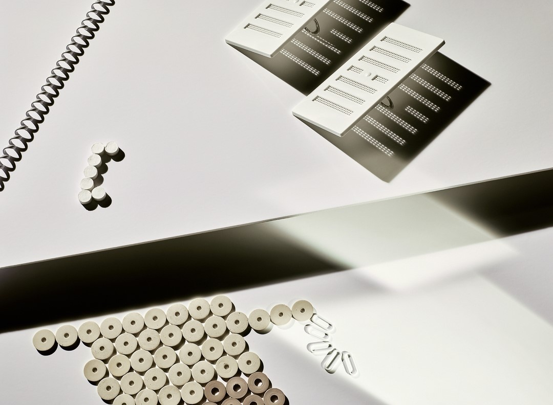 Overhead studio shot of white office supplies on a white backdrop with dark shadows creating contrast and visual interest.