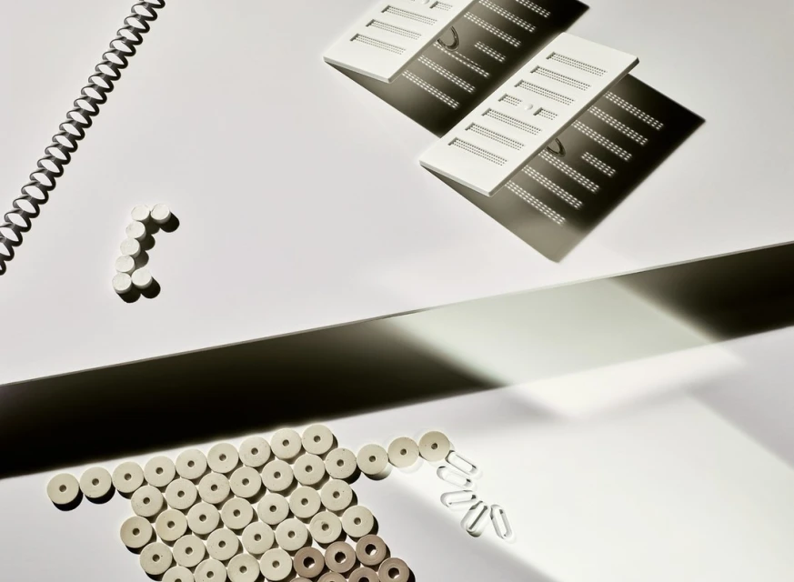 Overhead studio shot of white office supplies on a white backdrop with dark shadows creating contrast and visual interest.