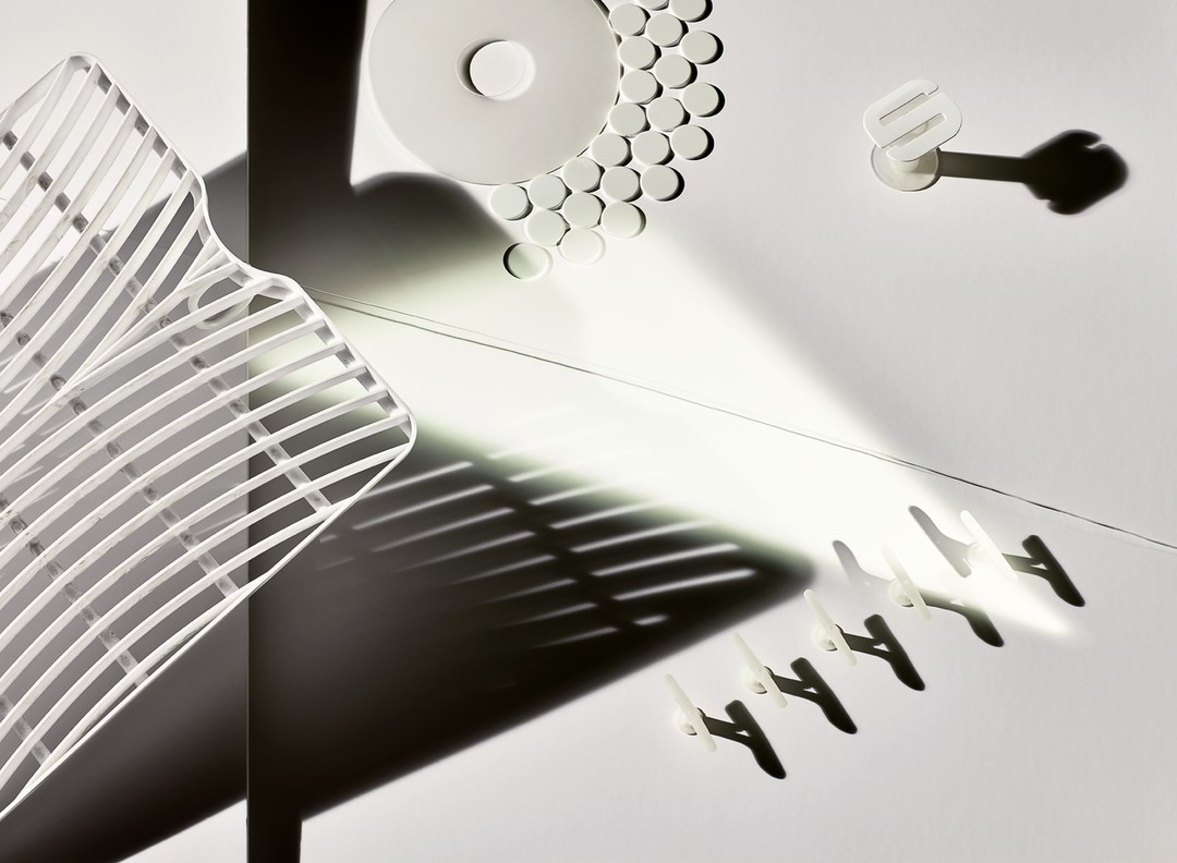 Abstract still life photograph features an arrangement of white household items with shadows creating strong lines and geometric shapes.