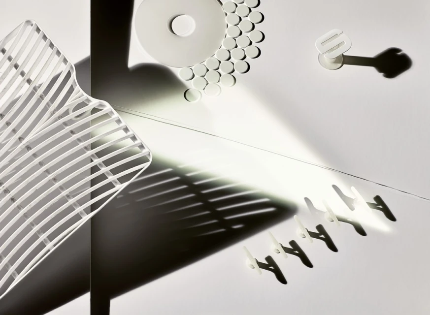 Abstract still life photograph features an arrangement of white household items with shadows creating strong lines and geometric shapes.