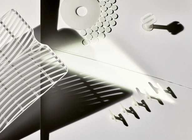 Abstract still life photograph features an arrangement of white household items with shadows creating strong lines and geometric shapes.