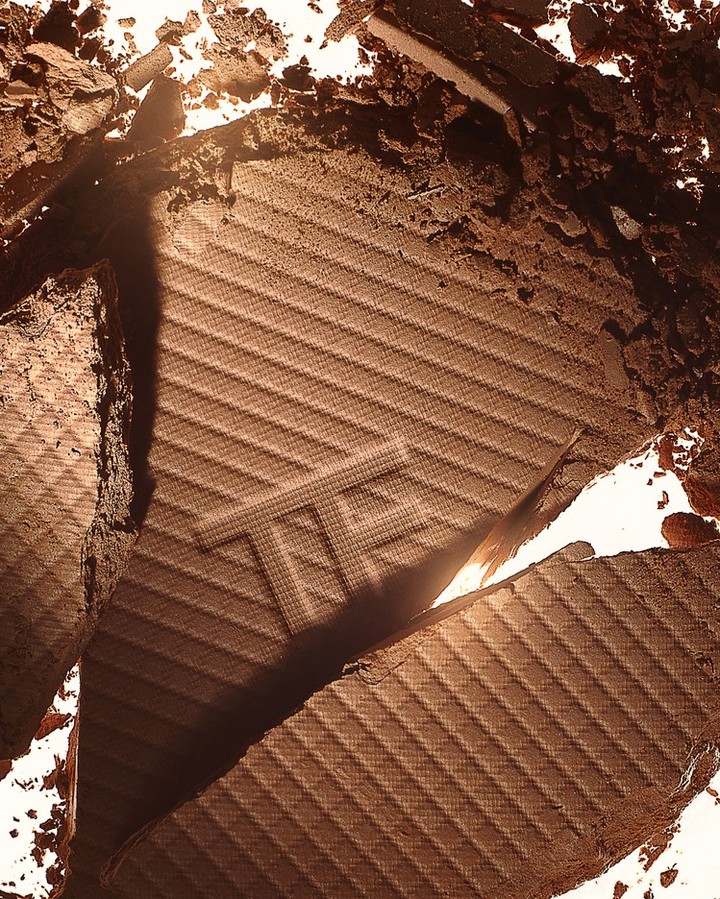 Close-up of a brown cosmetic bronzer or eyeshadow powder with the brand initials 'TF' visible, showcasing its textured surface.