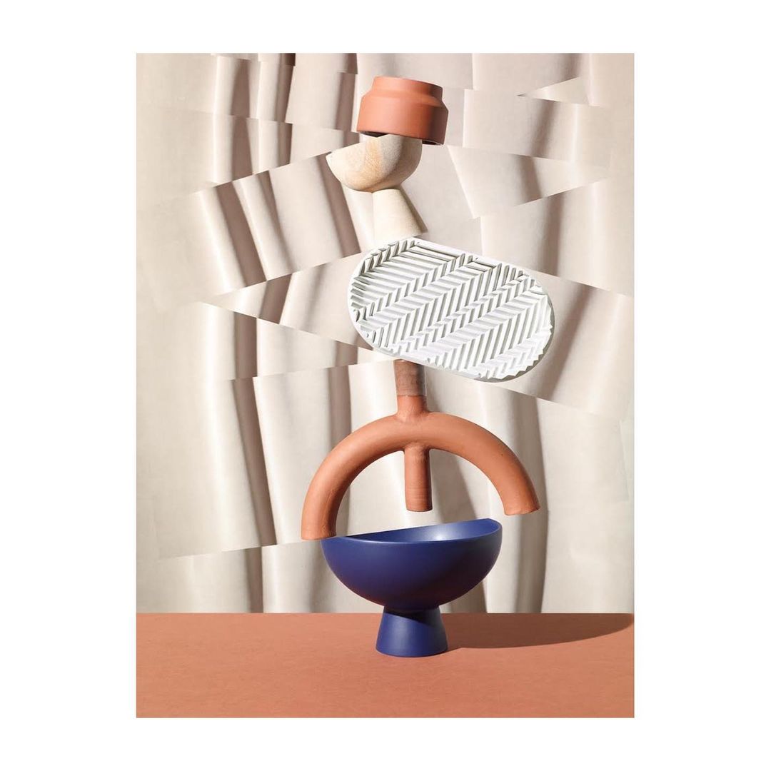 Abstract sculpture featuring pottery bowls and geometric shapes arranged against a textured backdrop with sharp shadows and color contrasts.