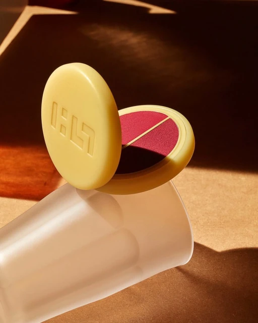 Beige makeup compact with blush on warm brown surface with graphic shadows and frosted glass - beauty and cosmetics product shot.