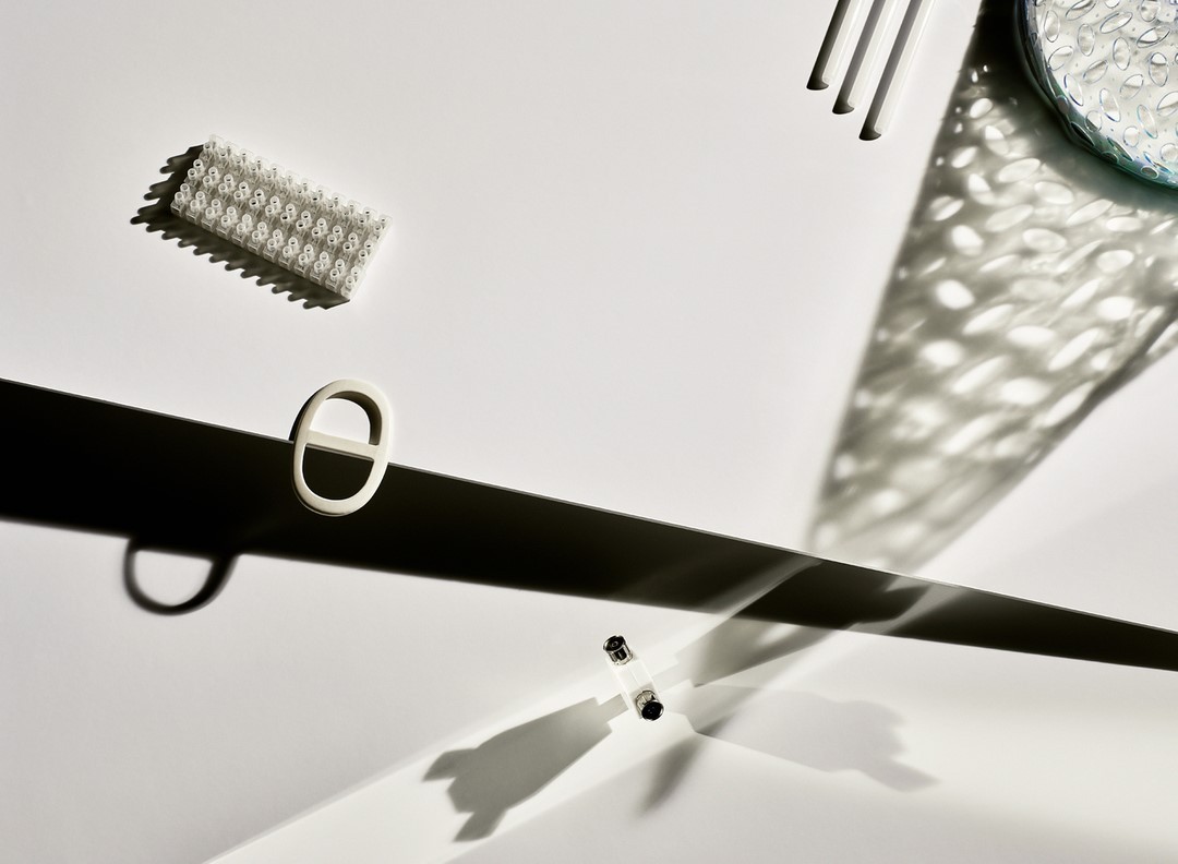 Studio shot of white electrical parts on a white background with strong shadows creating a high-contrast, minimalist tech product aesthetic.