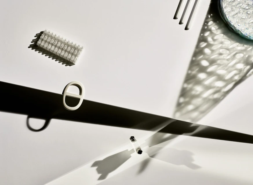 Studio shot of white electrical parts on a white background with strong shadows creating a high-contrast, minimalist tech product aesthetic.
