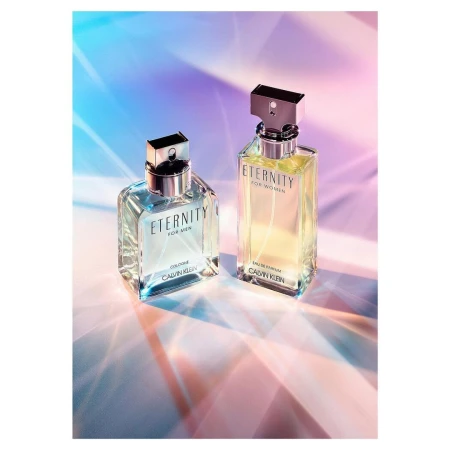 Two Calvin Klein Eternity perfume bottles, for men and women, arranged on a surface reflecting a colourful light pattern.