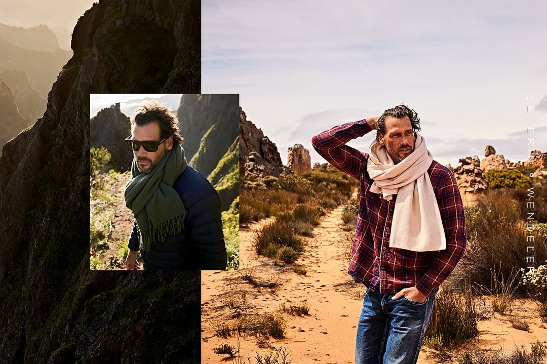 Man in a plaid shirt and scarf poses on a sandy path, with a split view showing mountain scenery and outdoor fashion.