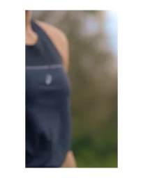 Close-up portrait of a person wearing a dark sleeveless athletic top against an out-of-focus natural green background