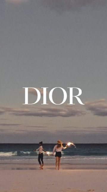 Two women walk along a beach at dusk towards the ocean. The scene is softly lit with the name 'DIOR' superimposed.