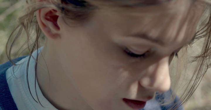 Extreme close-up portrait of a young person in natural light with stray hair strands