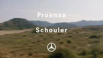 Proenza Schouler logo over a wide outdoor landscape featuring a grassy field with distant mountains under an overcast sky.