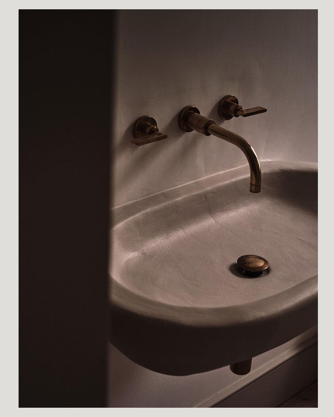 Close-up shot of a modern concrete bathroom sink with antique brass fixtures, creating a minimalist yet elegant design.