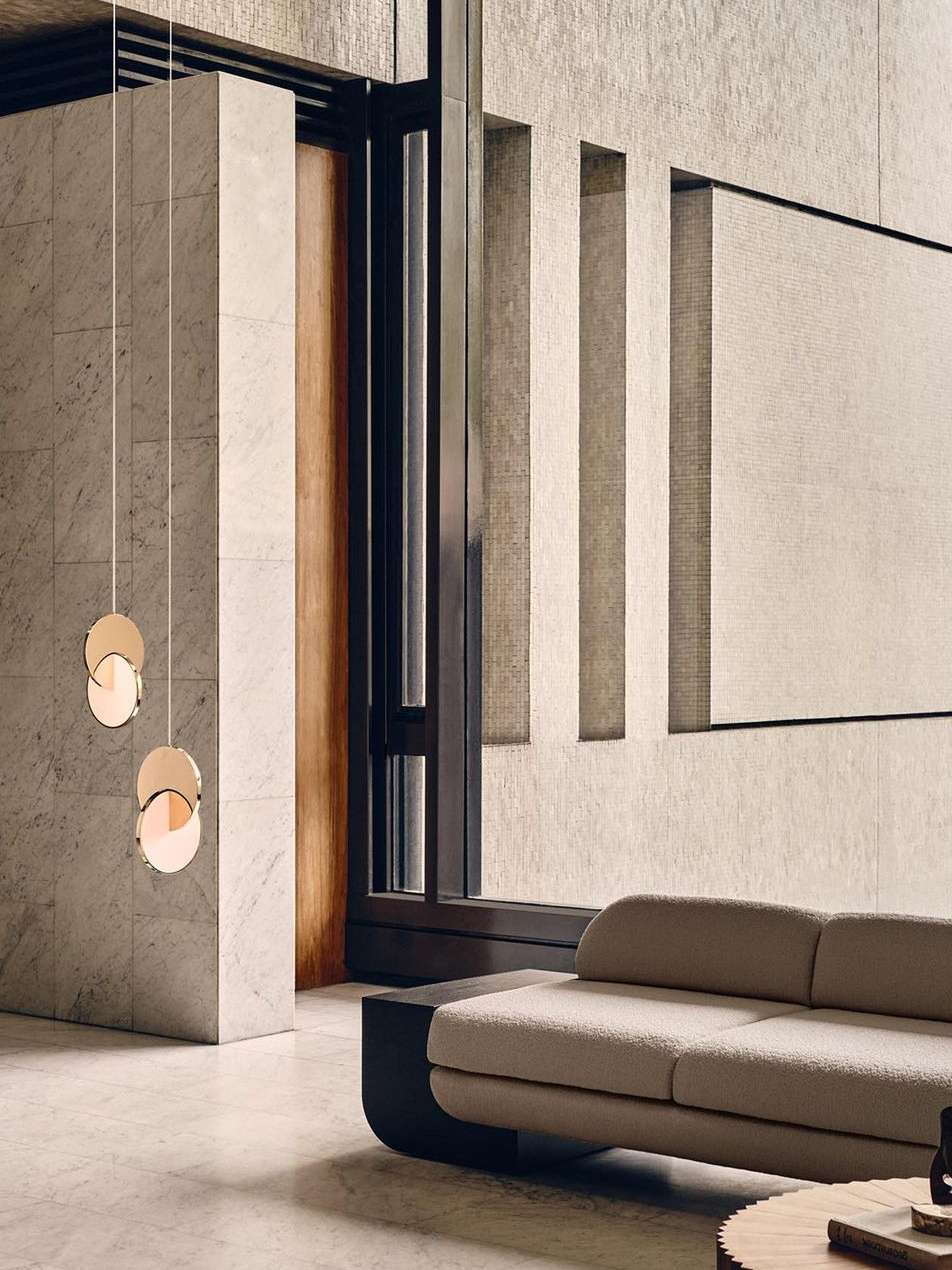 Minimalist interior featuring a modern sofa, hanging disc lights, and neutral color palette, creating a serene and sophisticated ambiance.