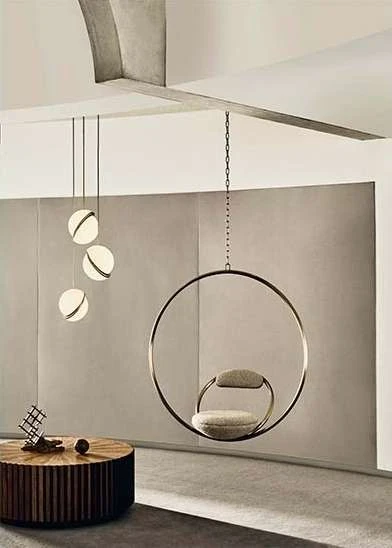 Interior view of a modern living room with a hanging chair, spherical pendant lights, a wood slat table, and neutral color palette.