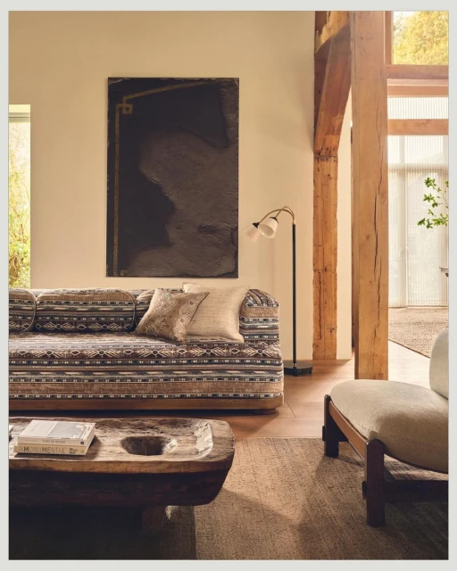 Living room interior with a patterned sofa, decorative pillows, a wooden coffee table, and an abstract art piece hanging on the wall.