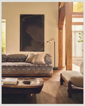 Living room interior with a patterned sofa, decorative pillows, a wooden coffee table, and an abstract art piece hanging on the wall.