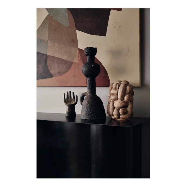Still life featuring three sculptural vases displayed on a sleek black console table with an abstract artwork in the background, showcasing modern design.