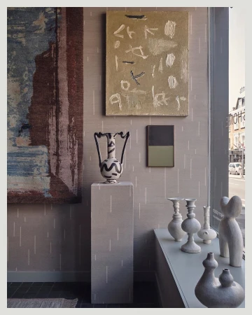 Interior space featuring neutral tones, abstract art, decorative vases, and a geometric pedestal, creating a modern, minimalist aesthetic.