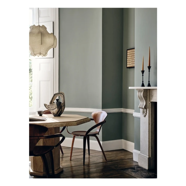 Dining room features olive green walls, hardwood floor, octagonal wood table with modern vase, chairs, and a white plaster fireplace.