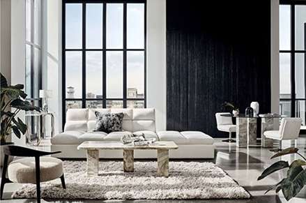 Living room interior featuring a white sofa, marble coffee table, textured rug, and dining set, set against large windows with a city view.