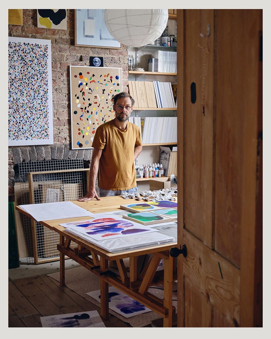 Indoor shot of an artist in his studio with colorful abstract paintings on display, showcasing his creative workspace and artistic endeavors.