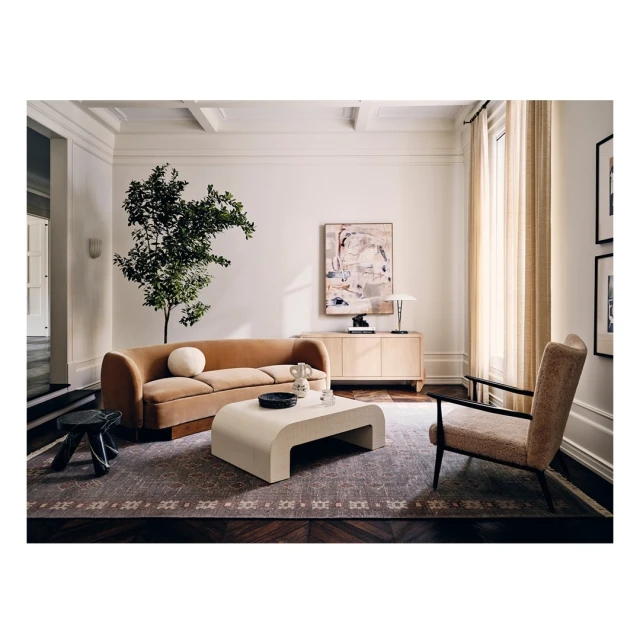 Modern living room interior with beige sofa, neutral tones, abstract art, decorative lighting, and parquet wood flooring.