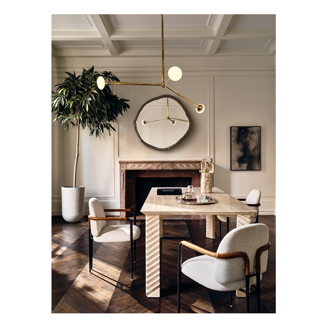 Dining room interior featuring a marble table, modern chandelier, upholstered chairs, and a potted plant, creating a stylish and inviting space.