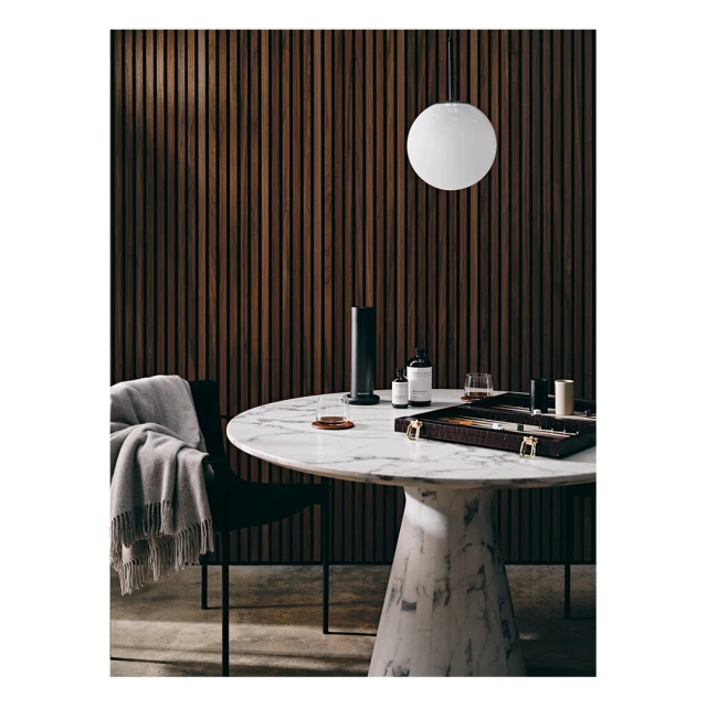 Interior shot of a marble table with decor, including diffuser, bottles, and game. The scene is lit by a spherical pendant light.