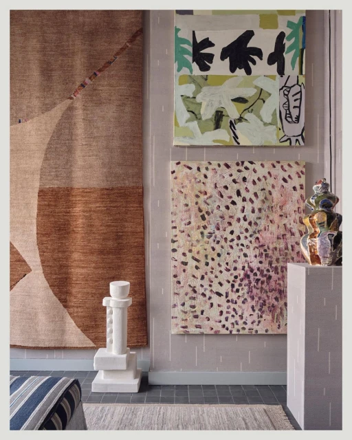 Interior view showcasing a geometric brown rug, two abstract paintings, and a white sculpture in a contemporary styled room.