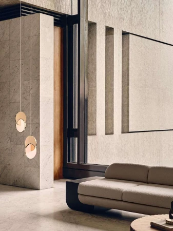 Modern interior with a neutral sofa, circular pendant lights, and large stone pillars in a spacious minimalist living area.