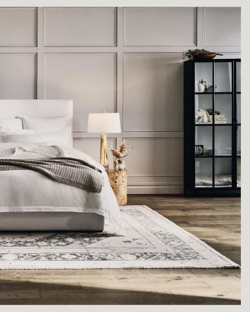 Modern bedroom interior with a white bed, patterned grey throw blanket, table lamp, and black glass cabinet by Ben Anders
