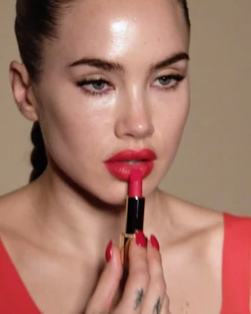 Close-up of a woman applying red lipstick, focusing on her face, hand holding the lipstick tube, and the red color palette.