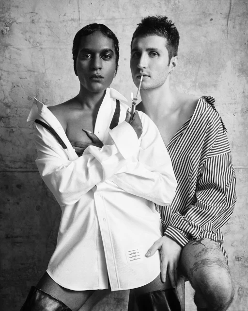 Black and white portrait of two adults, one with dark skin wearing a white shirt, and one with light skin wearing a striped shirt.