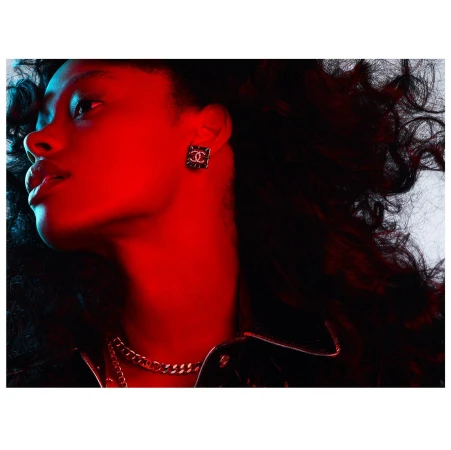 Profile shot of a woman with curly dark hair wearing a black leather jacket and gold chain. Red and blue lighting illuminates the scene.